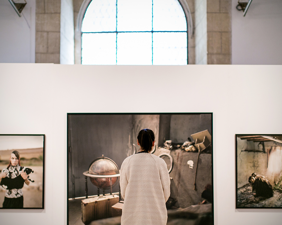 Mujer de espaldas observando cuadros en exposición en crucero del Hospital Real