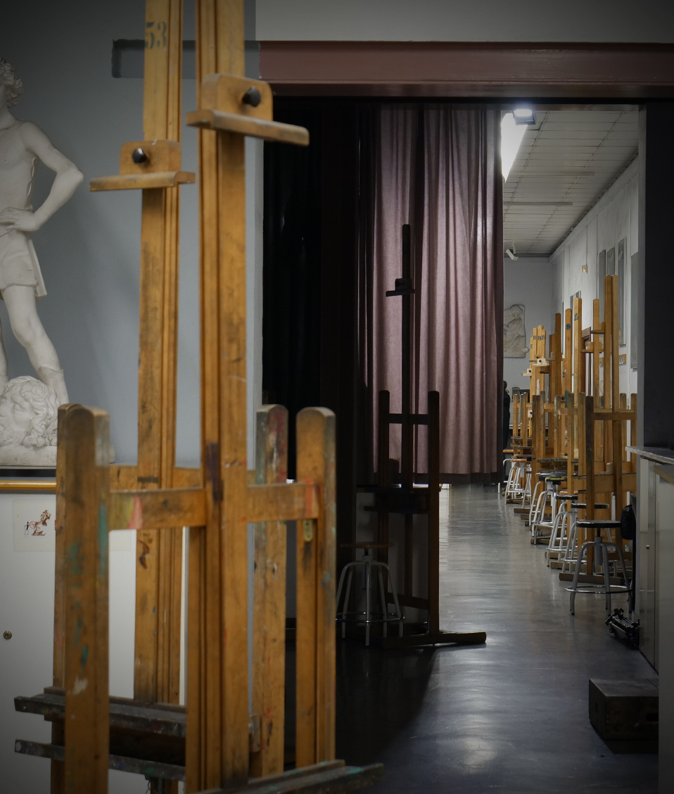 Esculturas a cada lado de la puerta de un aula de dibujo vacía con taburetes y caballetes